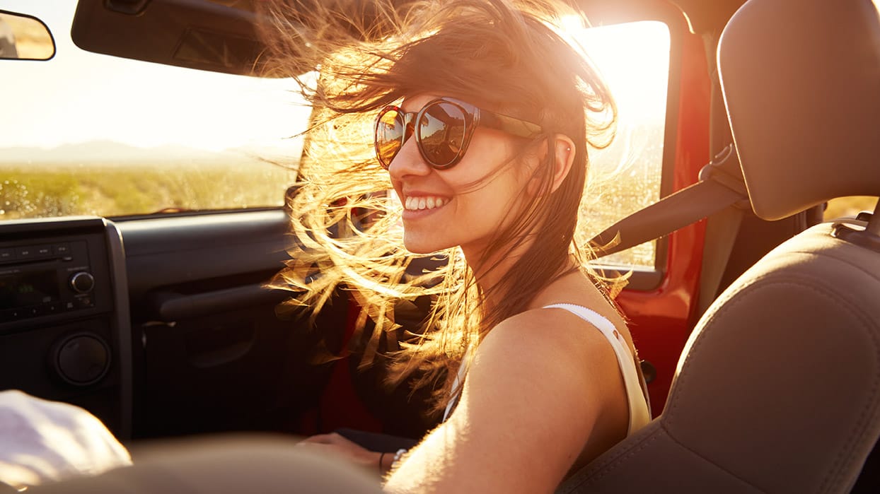 Hair blowing all-over on woman sitting by open vehicle window