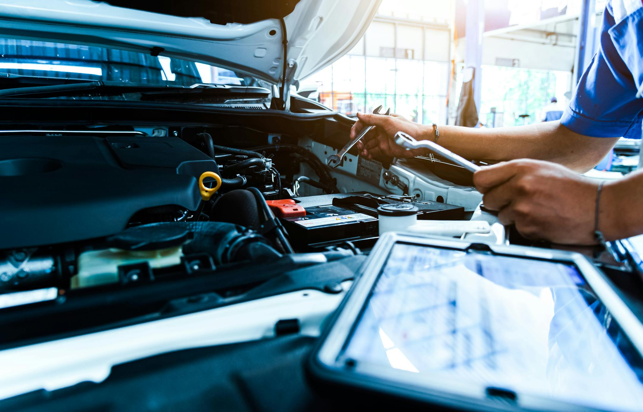 Auto mechanic are checking the condition of the car according to the month. The technician uses the tablet to check.