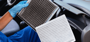 Burt Brothers technician replacing old, dirty cabin air filter with new, white cabin air filter.