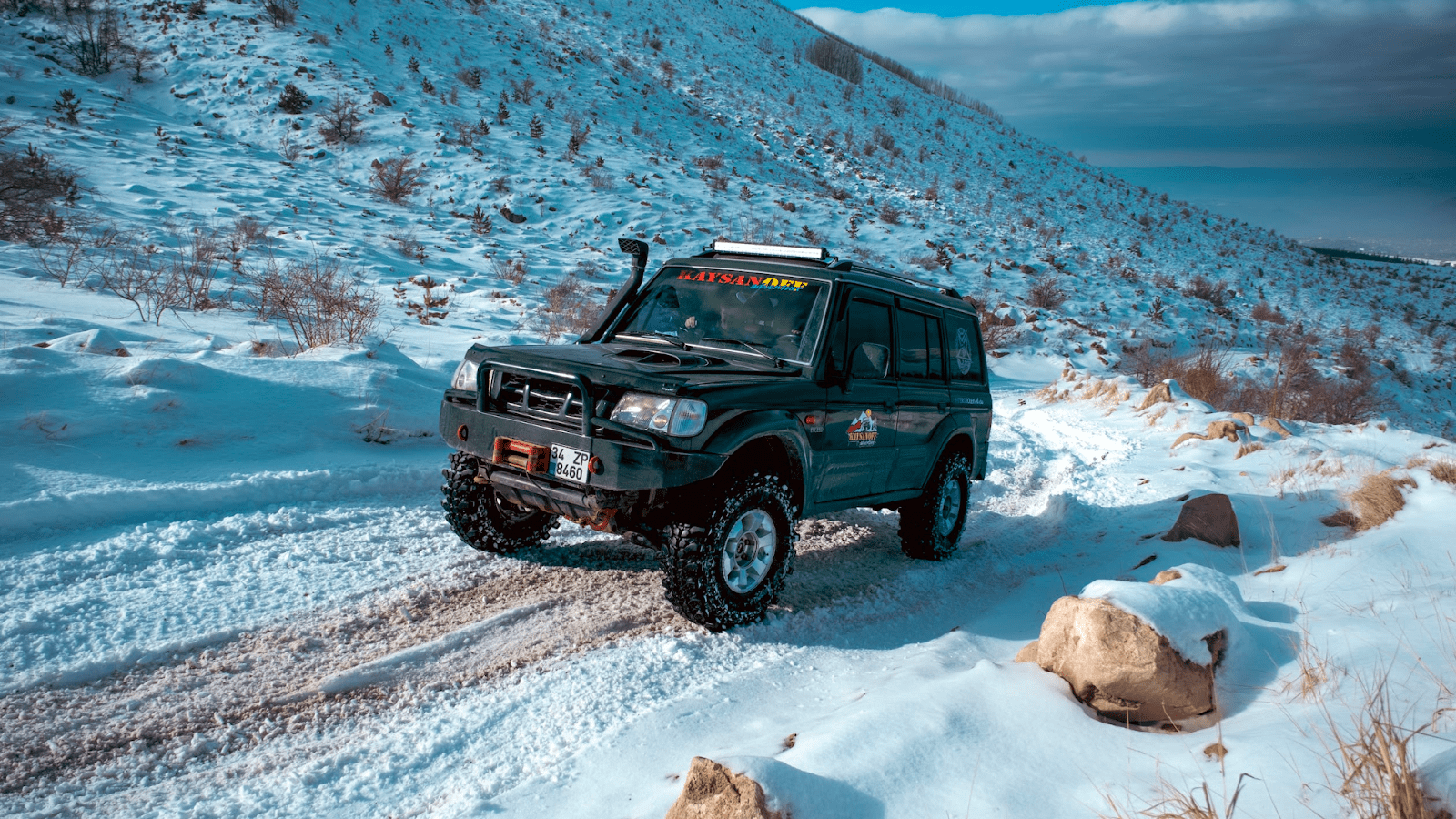Hyundai Galloper with offroad winter tires driving beside a mountain side