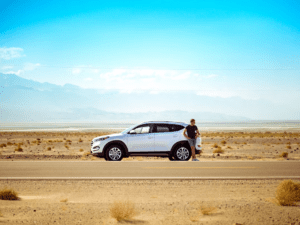 Picture of a man leaning on a parked SUV on the side of the Utah highway